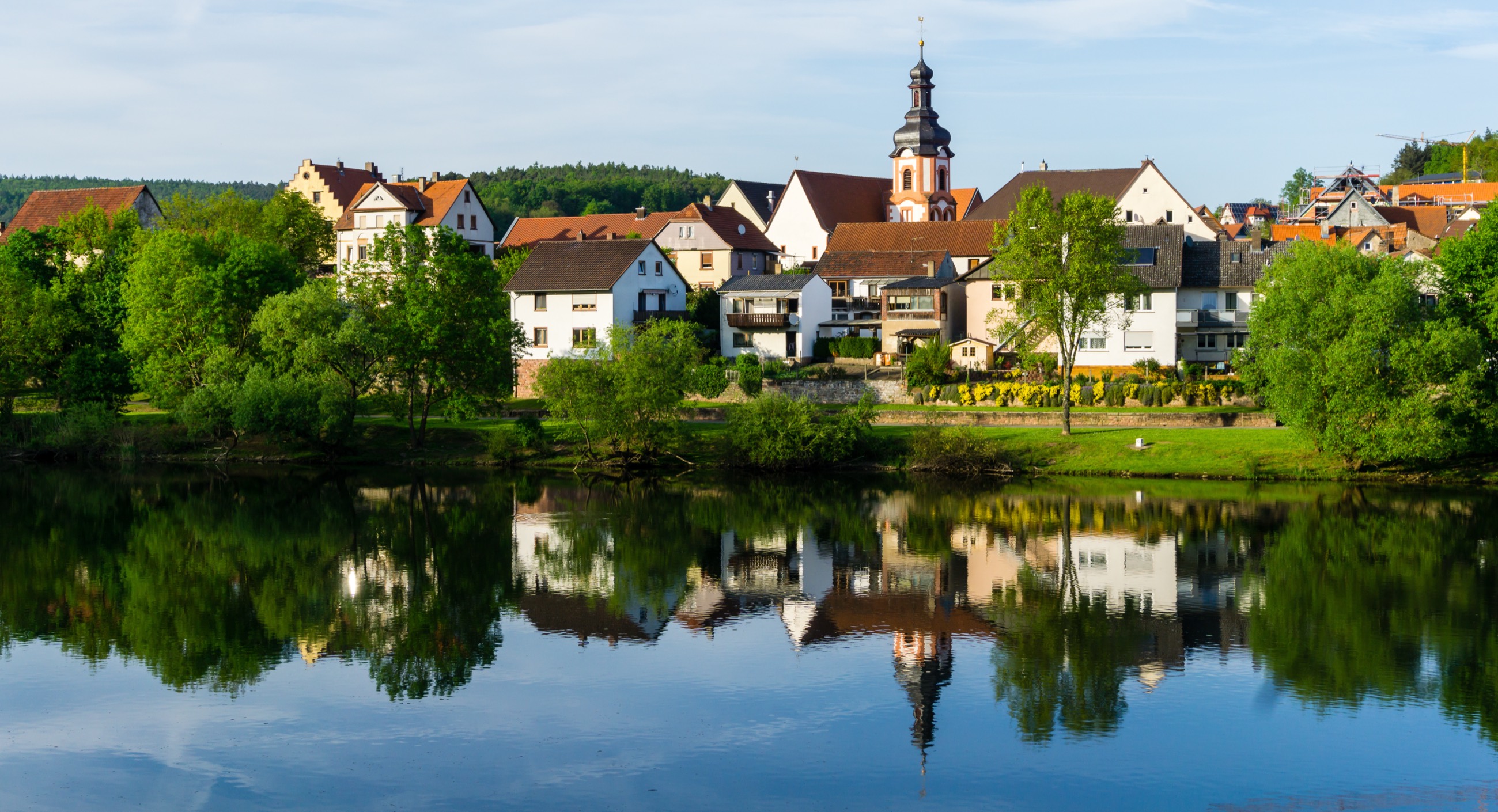 Kreuzwertheim am Main mit Kirche und Ortskern, der sich im Fluss spiegelt